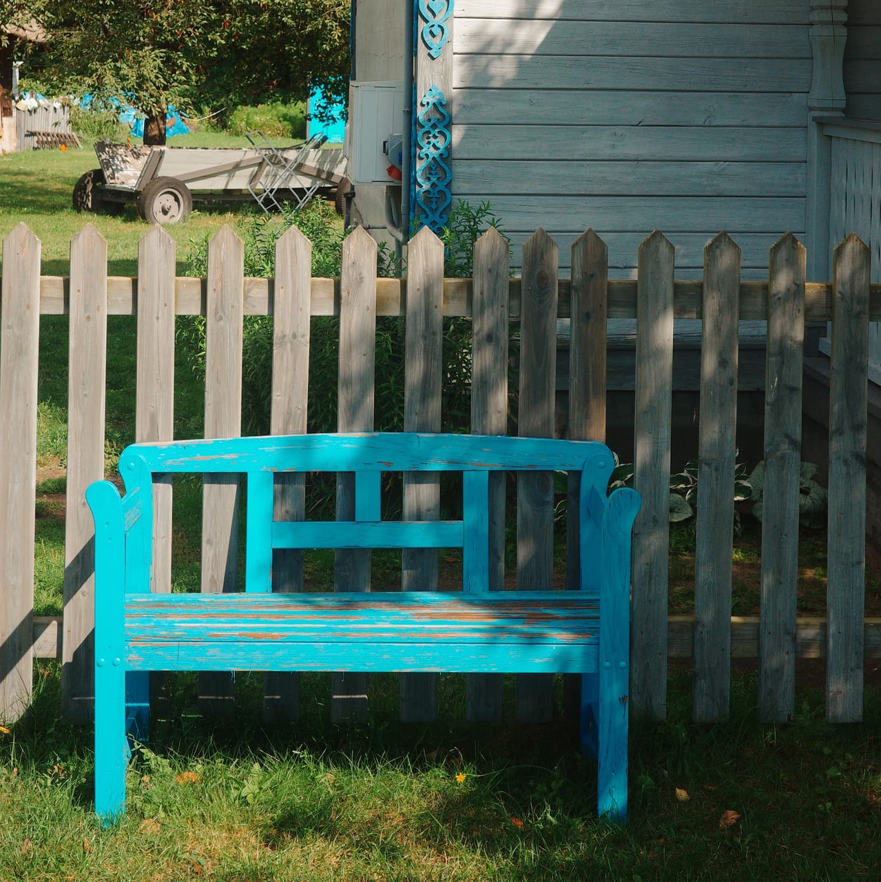 Peeling blue bench beside a wooden house with matching blue trim